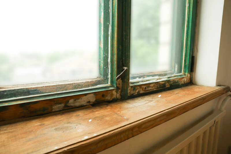 Rotting wood window frame with peeling paint on an older home