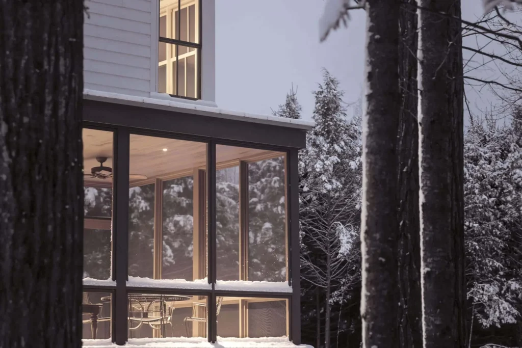 edge of home showing floor-to-ceiling windows covered in snow